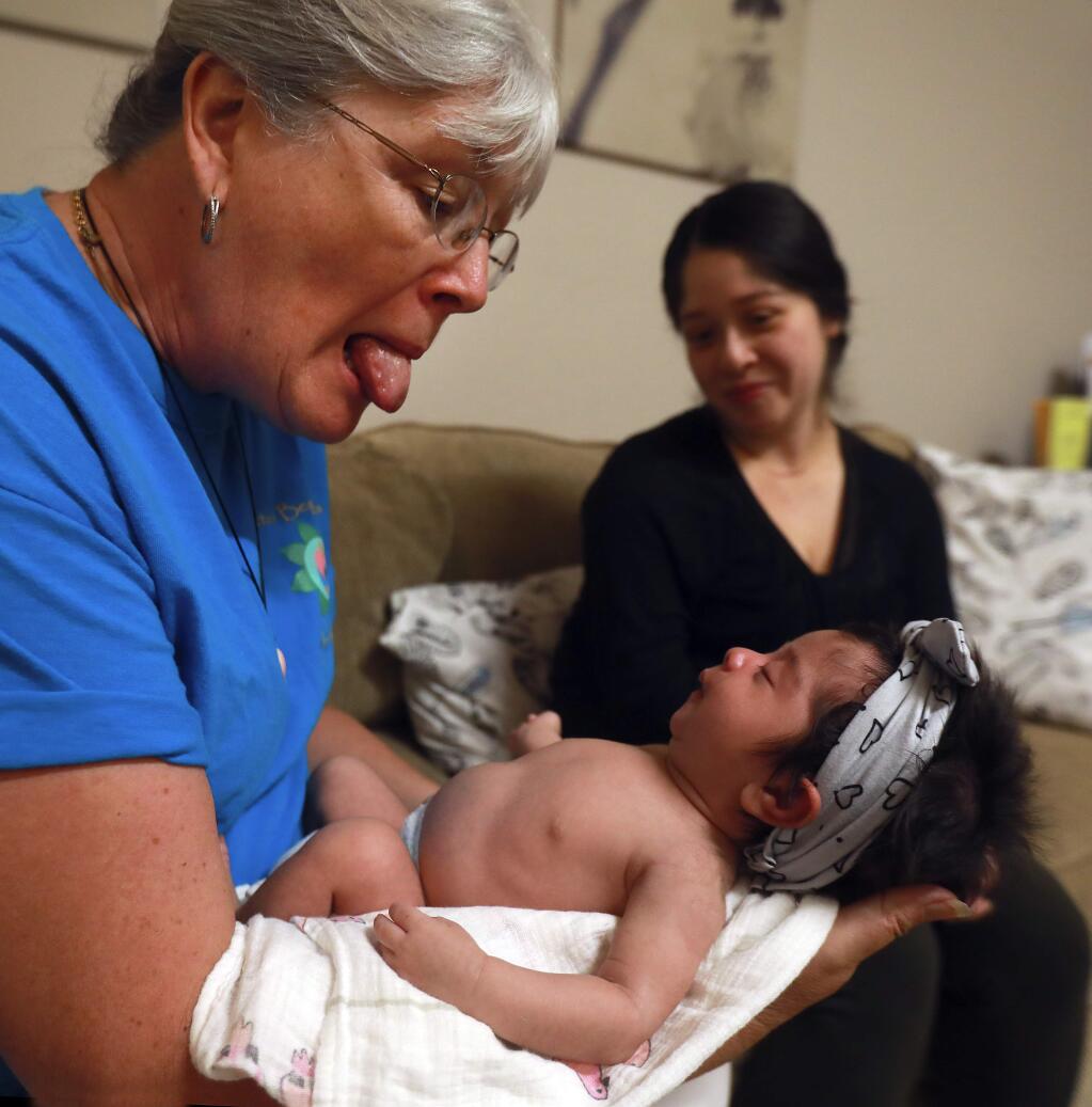 Nurse, midwife and lactation consultant Roseanne Gephart tries to encourage Abigail Viramontes to stick out her tongue while helping her mother Erika at the Breastfeeding Cafe, a service of the non-profit Better Beginnings. (John Burgess/The Press Democrat)