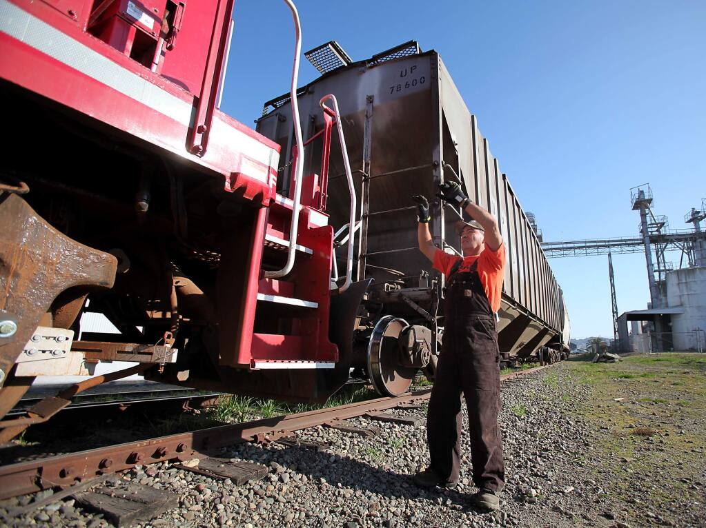 Northwestern Pacific Railroad conductor Frank Lovio signals to the train engineer while they pick up freight cars at Hunt & Behrens, Inc., in Petaluma on Wednesday, December 7, 2011.