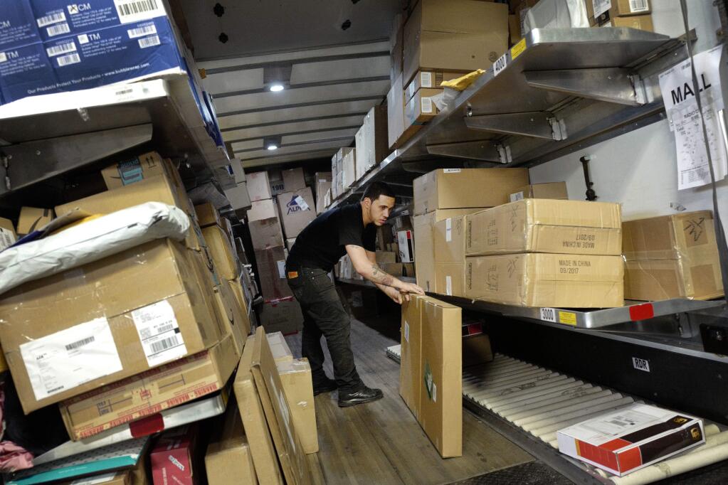 FILE- In this May 9, 2017, file photo, a UPS employee loads packages onto a truck at a company facility in New York. The job market is the tightest it has been in nearly five decades and online shopping is still growing at a double-digit rate. Businesses now need more workers at a time when fewer are available. UPS plans to hold nearly 170 job fairs around the country on a single day, Oct. 19, 2018. (AP Photo/Mark Lennihan, File)