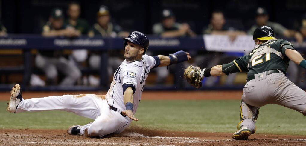 The Tampa Bay Rays' Kevin Kiermaier, left, slides around a tag by Oakland Athletics catcher Jonathan Lucroy to score on a sacrifice fly by Jake Bauers during the sixth inning Saturday, Sept. 15, 2018, in St. Petersburg, Fla. (AP Photo/Chris O'Meara)