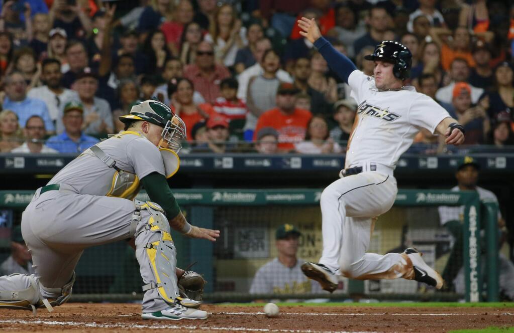 Oakland Athletics catcher Bruce Maxwell, left, reaches for the ball before tagging out the Houston Astros' Alex Bregman at home on a throw from center fielder Boog Powell in the fifth inning Saturday, Aug. 29, 2017, in Houston. (AP Photo/Richard Carson)