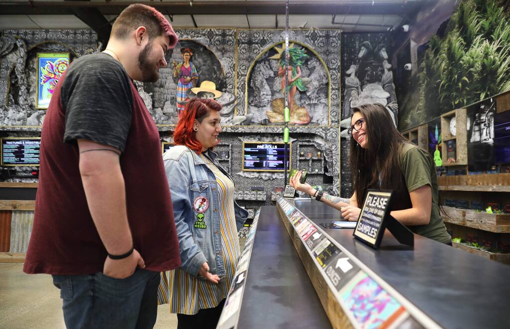 OrganiCann budtender Bianca Ortiz, right, helps customers Allison Bowers and Austin Morris with their purchase of Lavender Trainwreck in Santa Rosa on Tuesday, Aug. 28, 2018. (CHRISTOPHER CHUNG/ PD)