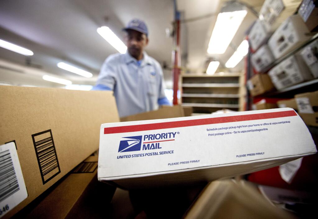 FILE - In this Thursday, Feb. 7, 2013, file photo, packages wait to be sorted in a Post Office as U.S. Postal Service letter carrier Michael McDonald, gathers mail to load into his truck before making his delivery run, in Atlanta. (AP Photo/David Goldman, File)