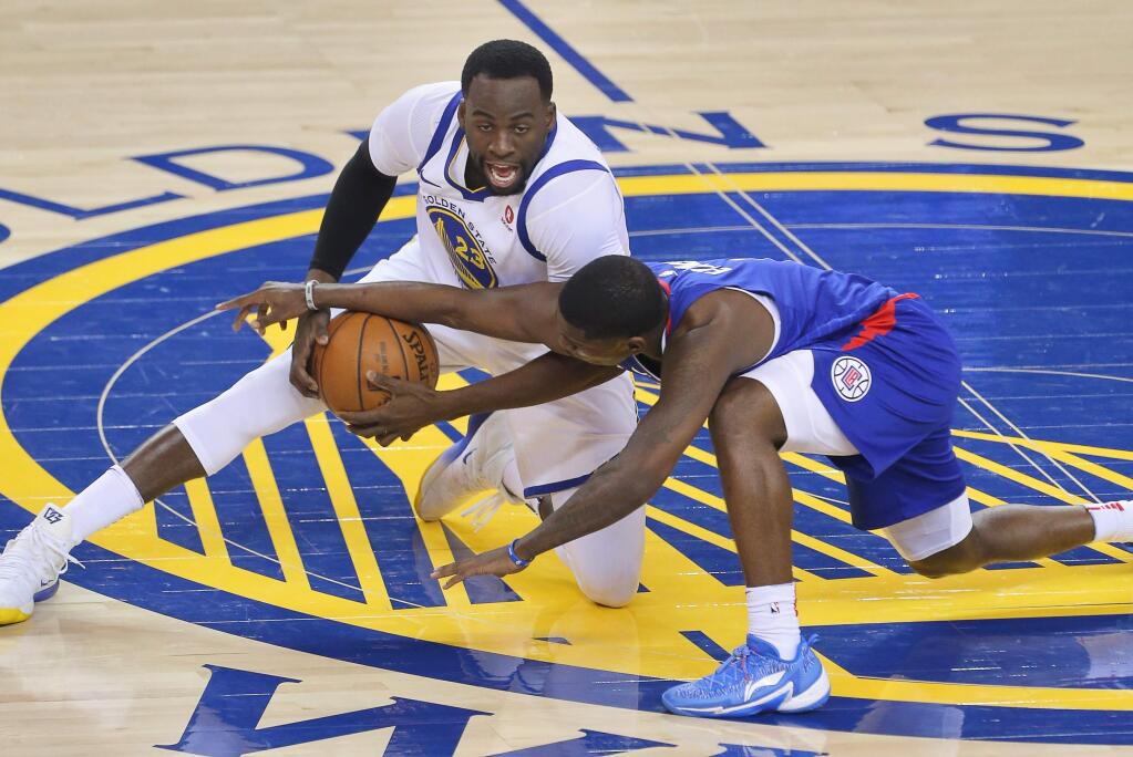 Golden State Warriors forward Draymond Green grabs a loose ball away from Los Angeles Clippers guard Jawun Evans during their game in Oakland on Wednesday, Jan. 10, 2018. (Christopher Chung / The Press Democrat)