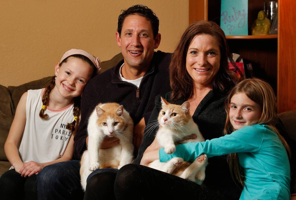 Cathleen Cavin and Brian Herrera hold their respective cats Ozzy and Butter, along with Cathleen's daughter Cali Joyce, 8, right, and Brian's daughter Ruby Herrera, 9, in Cotati, California on Wednesday, February 15, 2017. (Alvin Jornada / The Press Democrat)