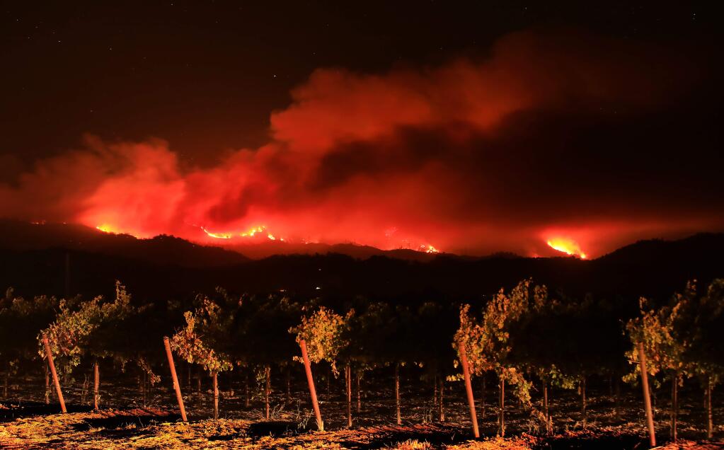 Headlights illuminate a vineyard in the Alexander Valley as the the Kincade fire burns in the Mayacamas Mountains, Friday, Oct. 25, 2019. (Kent Porter / The Press Democrat) 2019