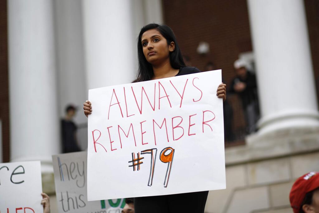 University of Maryland student Ro Nambiar holds a sign as people gather at a 'Justice for Jordan' rally in remembrance of offensive lineman Jordan McNair, Thursday, Nov. 1, 2018, on the university's campus in College Park, Md. Maryland President Wallace Loh fired football head coach DJ Durkin Wednesday, about five months after McNair collapsed on a practice field and later died of heatstroke. (AP Photo/Patrick Semansky)