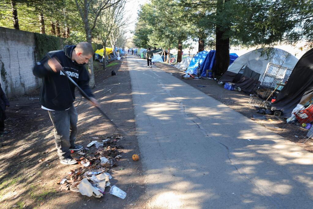 Chad Carver rakes trash along the Joe Rodota Trail, where he resides along with an estimated 220 other homeless, in Santa Rosa on Monday, Jan. 6, 2020. (CHRISTOPHER CHUNG/ PD)