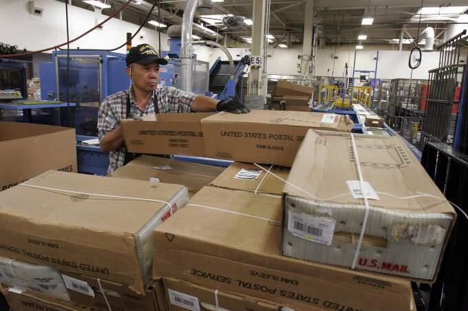 A postal worker sorts packages at the Petaluma mail facility. (PD File)