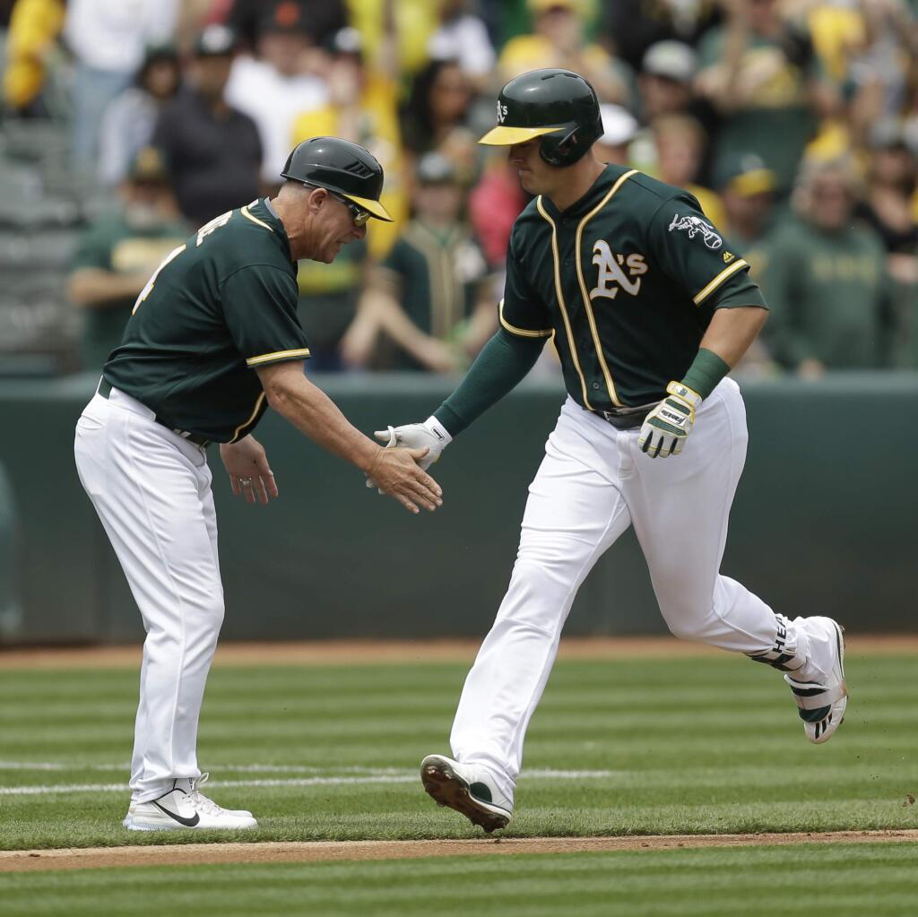 Oakland Athletics' Ryon Healy, right, is congratulated by third base coach Chip Hale after hitting a two-run home run off Seattle Mariners pitcher Ariel Miranda in the first inning of a game Saturday, April 22, 2017, in Oakland. (AP Photo/Ben Margot)
