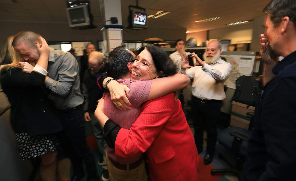Santa Rosa Press Democrat Executive Editor Catherine Barnett embraces reporter Martin Espinoza after the Press Democrat was given the Pulitzer Prize for Breaking News Reporting awarded to the staff of the Press Democrat, Monday April 16, 2018 for coverage of the October fires. At left, reporters JD Morris and Christi Warren celebrate along with Director of Photography Chad Surmick, middle left, with City Editors Brett Wilkison and Steve Levin, middle right, and reporter Kevin McCallum. (Kent Porter / The Press Democrat) 2018