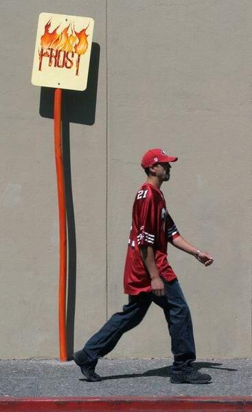 The sign 'Frost' atop a crooked pole on Fifth Street off Mendocino Avenue is passed by a pedestrian headed for a nearby sports bar Sunday September 7 in Santa Rosa. Jacob McAdam, Maria Carrillo High School senior, created the sign participating in the ArtStart summer youth program.