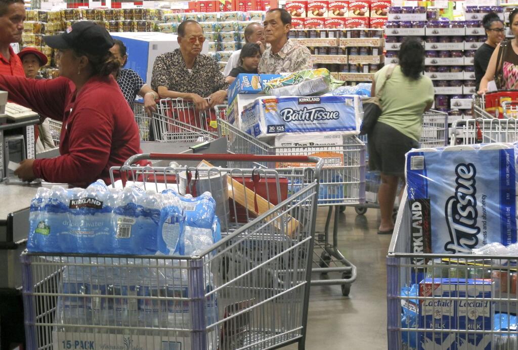 Shoppers stock up on cases of bottled water and other supplies in preparation for a hurricane and tropical storm heading toward Hawaii at the Iwilei Costco in Honolulu on Tuesday, Aug. 5, 2014. Two big storms so close together is rare in the eastern Pacific, and Hurricane Iselle could make landfall by Friday and Tropical Storm Julio could hit two or three days later, weather officials said. (AP Photo/Audrey McAvoy)