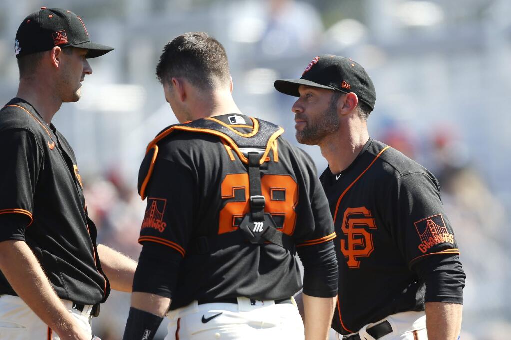San Francisco Giants manager Gabe Kapler, right, talks with Giants starting pitcher Drew Smyly, left, and Giants catcher Buster Posey (28) during the second inning of a spring training game against the Arizona Diamondbacks, Monday, Feb. 24, 2020, in Scottsdale, Ariz. (AP Photo/Ross D. Franklin)