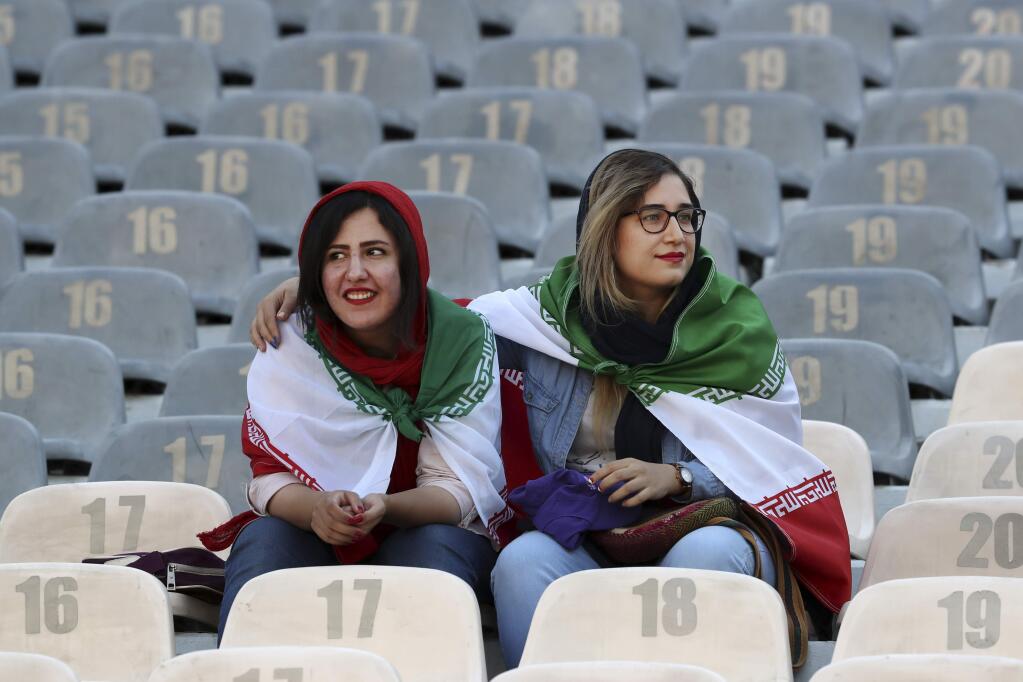 Iranian women wear their country's flag on their shoulders at the Azadi Stadium for the 2022 World Cup qualifier soccer match between Iran and Cambodia, in Tehran, Iran, Thursday, Oct. 10, 2019. Iranian women were freely allowed into the stadium for the first time in decades. The decision follows the death of a young woman who set herself on fire after hearing she could face prison time for sneaking into an Iranian soccer match disguised as a man. (AP Photo/Vahid Salemi)