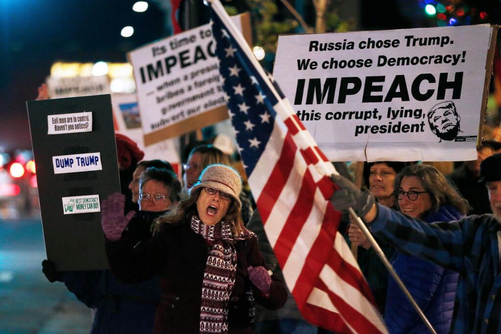 Lorena Porfido, at left, of Bodega Bay encourages passing motorists to honk their car horns during a rally supporting the impeachment of President Donald Trump, at Old Courthouse Square in Santa Rosa, California, on Tuesday, December 17, 2019. (Alvin Jornada / The Press Democrat)