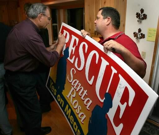 (File photo) Jerry Bender, the husband of Santa Rosa City Council member Jane Bender signs a Measure O poster held by the Vice President Santa Rosa Firefighters Local 1401, Tim Doherty in Santa Rosa, Tuesday November 2, 2004 (Kent Porter/The Press Democrat)