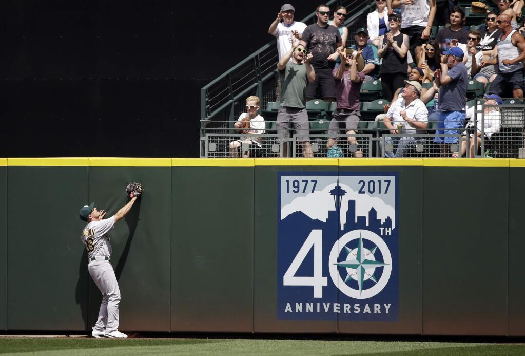 Oakland Athletics center fielder Jaycob Brugman watches as a fan tries to catch the home run ball of Seattle Mariners' Nelson Cruz in the fourth inning of a baseball game Sunday, July 9, 2017, in Seattle. (AP Photo/Elaine Thompson)