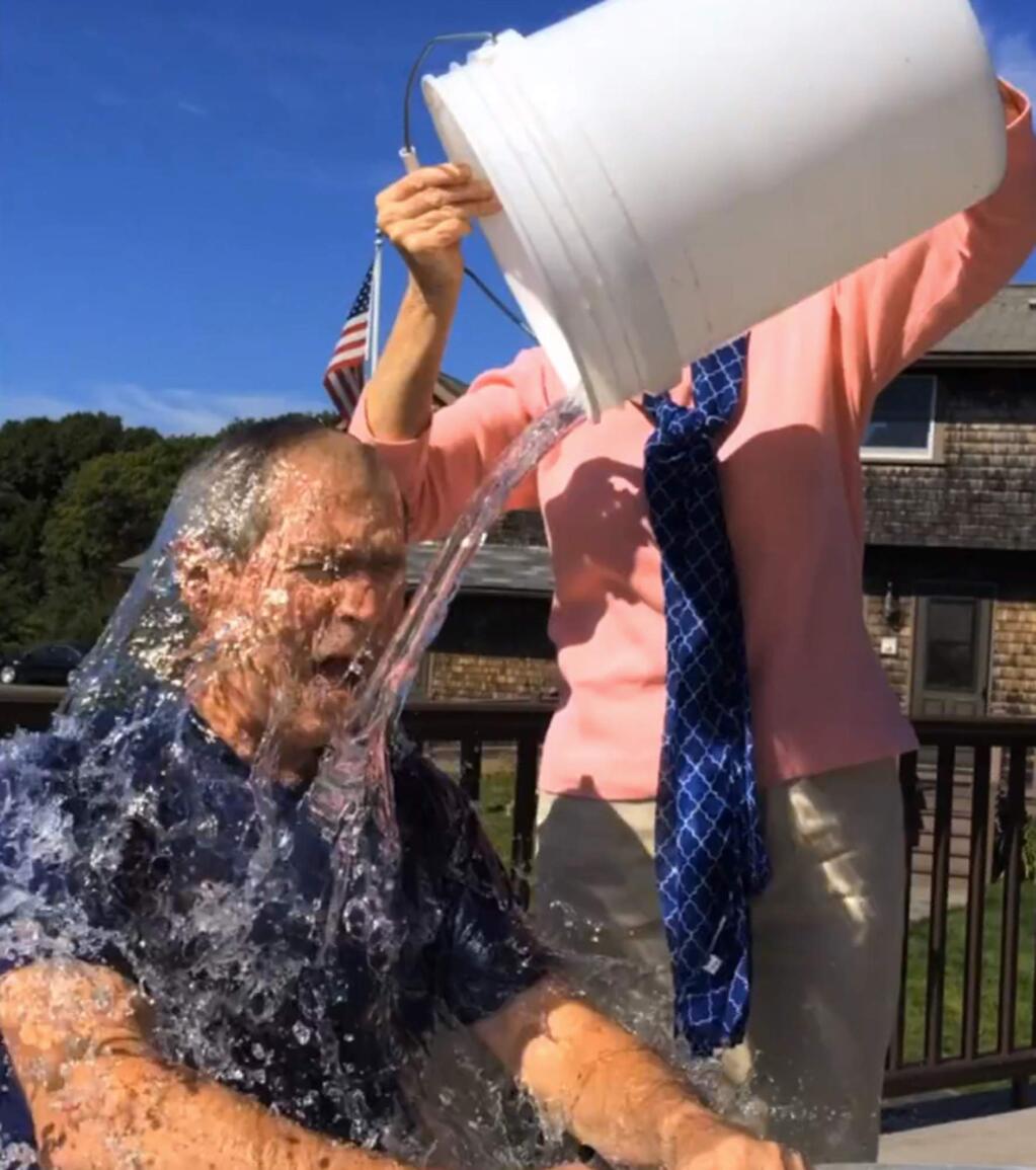 In this image from video posted on Facebook, courtesy of the George W. Bush Presidential Center, former President George W. Bush participates in the ice bucket challenge with the help of his wife, Laura Bush, in Kennebunkport, Maine. The challenge has caught on with notable figures participating in the campaign to raise money for the fight against ALS, or Lou Gehrig's disease. (AP Photo/Courtesy George W. Bush Presidential Center)