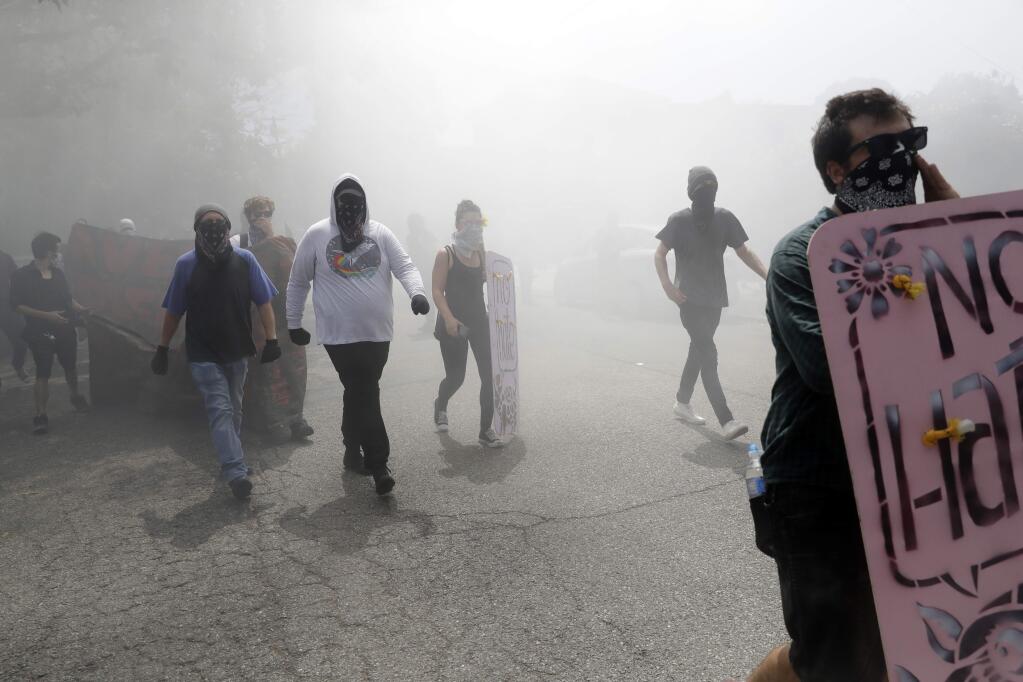 Demonstrators walk through a cloud of tear gas during a free speech rally Sunday, Aug. 27, 2017, in Berkeley, Calif. (AP Photo/Marcio Jose Sanchez)