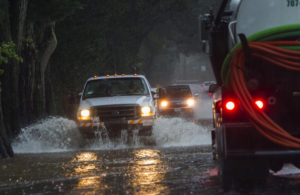 Photos by Robbi Pengelly/Index-TribuneVehicles move slowly along a flooded Watmaugh Road near Broadway.