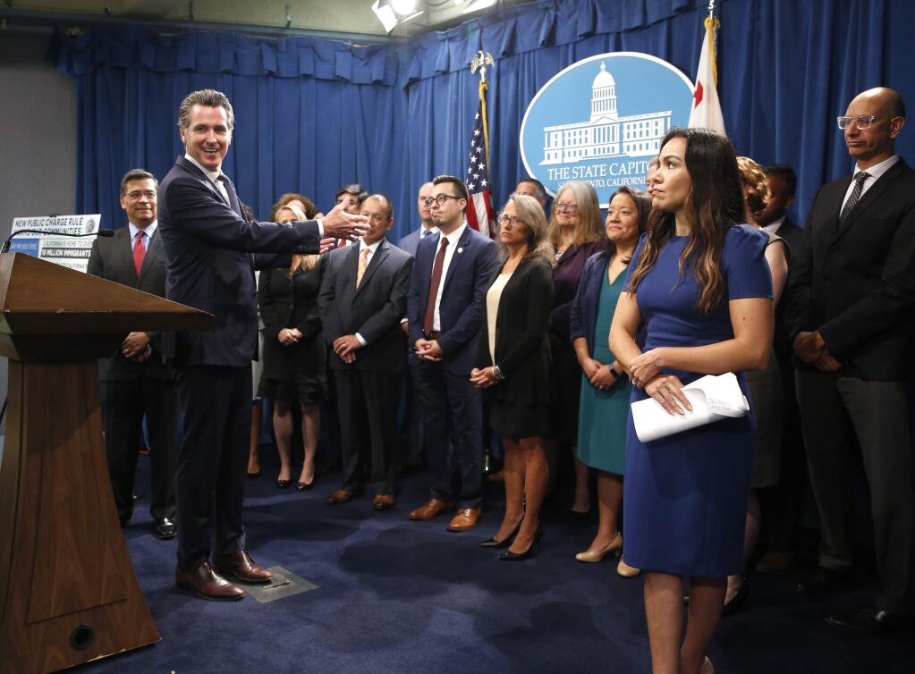 California Gov. Gavin Newsom, second from left, gestures towards a group of immigrant advocates and service providers as he discusses the effects of the Trump administration's new rules blocking green cards for many immigrants who receive government assistance, during a news conference in Sacramento, Calif., Friday, Aug. 16, 2019. Newsom and Attorney General Xavier Becerra, left, announced that California has joined three other states and the District of Columbia in a lawsuit filed Friday against some of the administration's most aggressive moves to restrict legal immigration that are supposed to take effect in October. (AP Photo/Rich Pedroncelli)