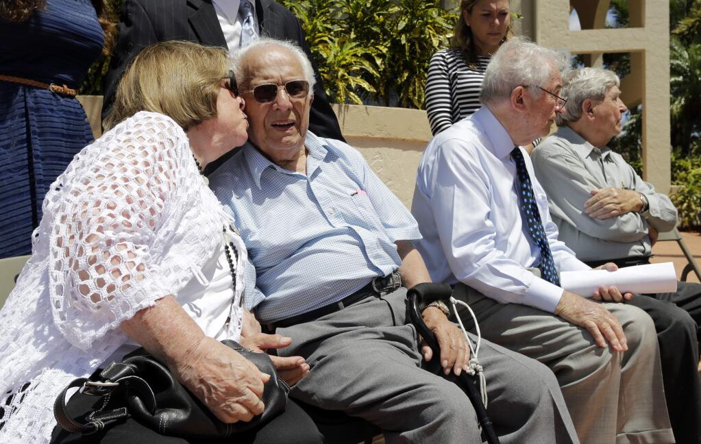 Shirley Rubin, left, kisses holocaust survivor Morric Jusovic after he spoke at a news conference in support of Boca Raton's decision to drop German insurance giant Allianz as sponsor of a professional golf tournament, Monday, April 24, 2017, in Boca Raton, Fla. Survivors say that this could renew momentum for their years-long effort to gain the right to sue the company over stolen Jewish policies during the Nazi era. (AP Photo/Lynne Sladky)