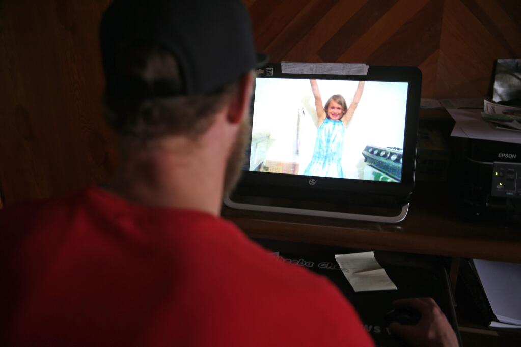 In this Jan. 13, 2015 photo, Ian Sullivan sits in his home office looking at pictures of his late six year old daughter Veronica, who was murdered in the 2012 Aurora movie theater shooting attack, in Evergreen, Colo. Sullivan's life was forever darkened when a heavily armed gunman opened fire in a movie theater where young Veronica and Sullivan's x-wife were watching a movie, leaving 12 dead, including his daughter Veronica. (AP Photo/Brennan Linsley)