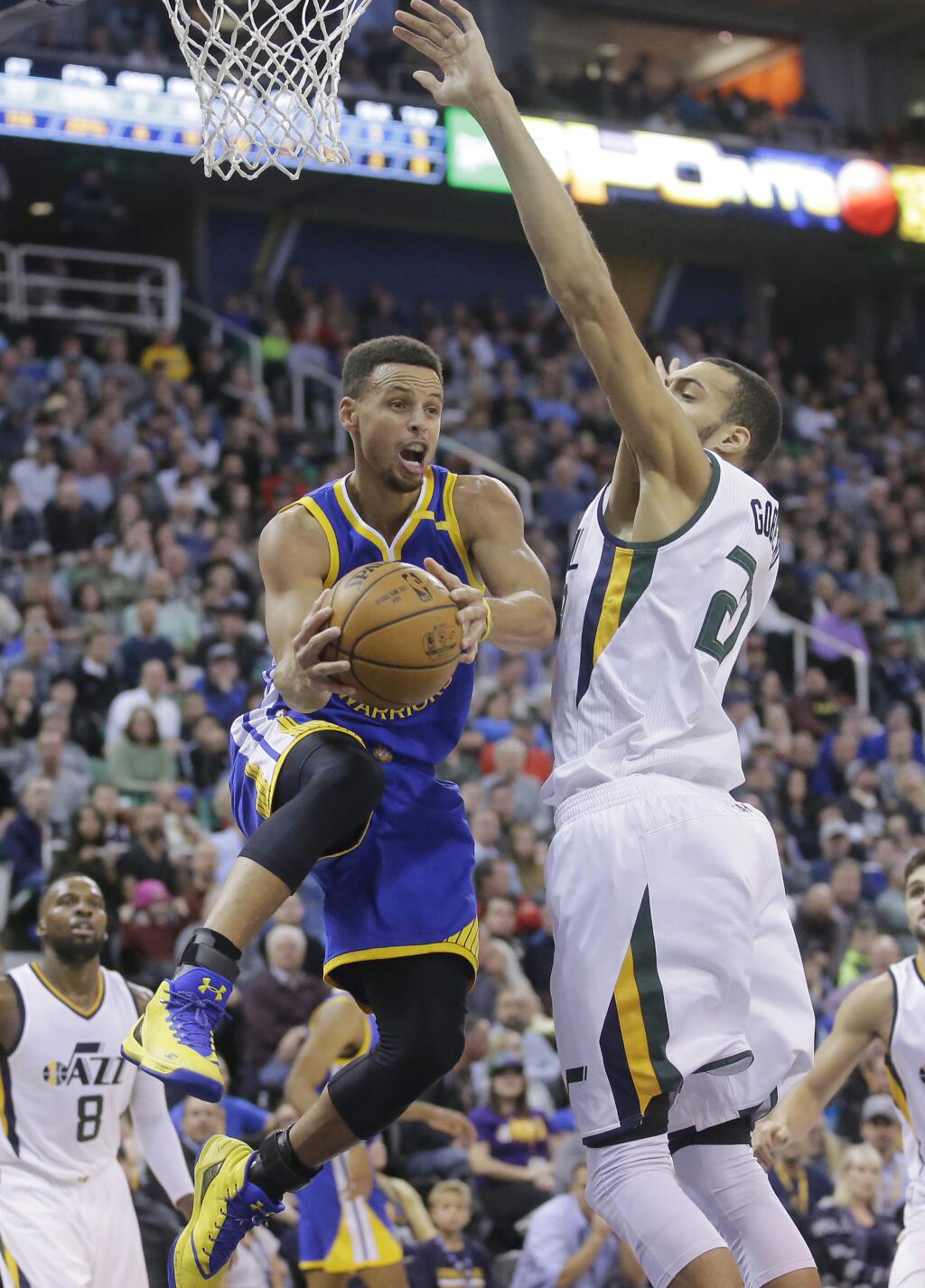 Golden State Warriors guard Stephen Curry, left, passes the ball as Utah Jazz center Rudy Gobert, right, defends in the first half during an NBA basketball game Thursday, Dec. 8, 2016, in Salt Lake City. (AP Photo/Rick Bowmer)