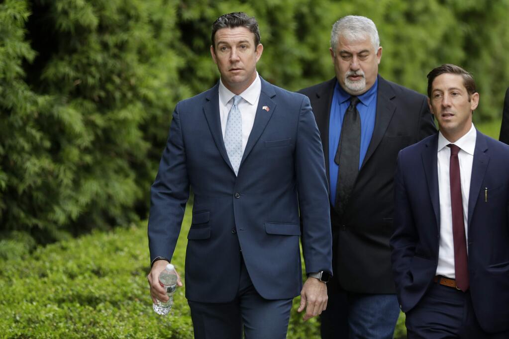 Convicted ex-Rep. Duncan Hunter, left, walks towards a court building for sentencing Tuesday, March 17, 2020, in San Diego. Hunter faces up to five years in prison after pleading guilty on a corruption charge. Hunter served six terms representing one of Southern California's last solidly Republican districts before he resigned. (AP Photo/Gregory Bull)