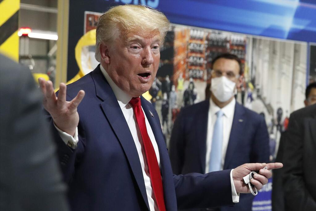 President Donald Trump holds a face mask in his left hand as speaks during a tour of Ford's Rawsonville Components Plant that has been converted to making personal protection and medical equipment, Thursday, May 21, 2020, in Ypsilanti, Mich. (AP Photo/Alex Brandon)