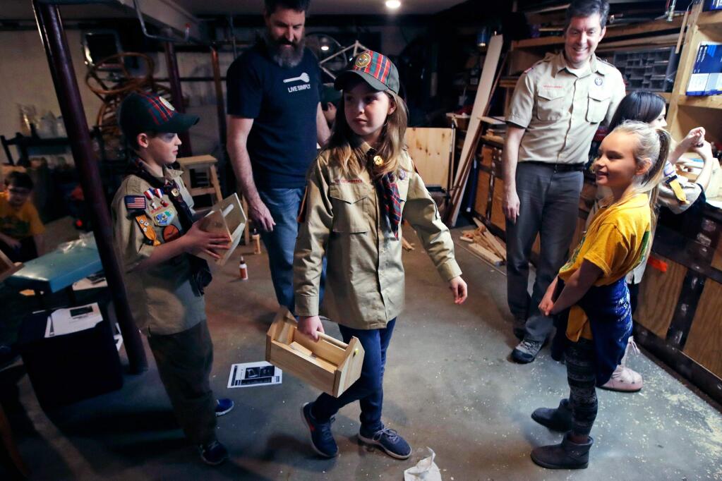 FILE - In this March 1, 2018, file photo, Tatum Weir, center, carries a tool box she built as her twin brother Ian, left, follows after a Cub Scout meeting in Madbury, N.H. Fifteen communities in New Hampshire are part of an 'early adopter' program to allow girls to become Cub Scouts and eventually Boy Scouts. For 108 years, the Boy Scouts of America's flagship program for older boys has been known simply as the Boy Scouts. With girls soon entering the ranks, the BSA says that iconic name will change to “Scouts BSA.” The change will take effect in February 2019. (AP Photo/Charles Krupa, File)