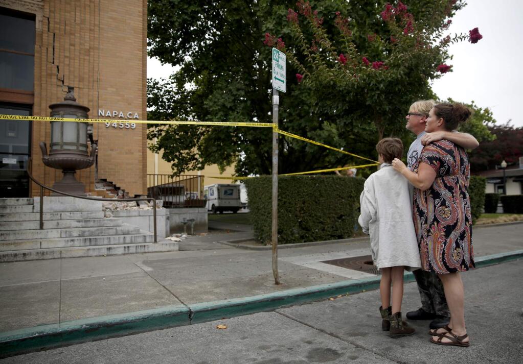 Stuart Atkinson, his partner Julie Green, and daughter Lily Atkinson, 10, look at the downtown Post Office after it was damaged during a 6.0 earthquake on Sunday, August 24, 2014 in Napa.(BETH SCHLANKER/ PD FILE)