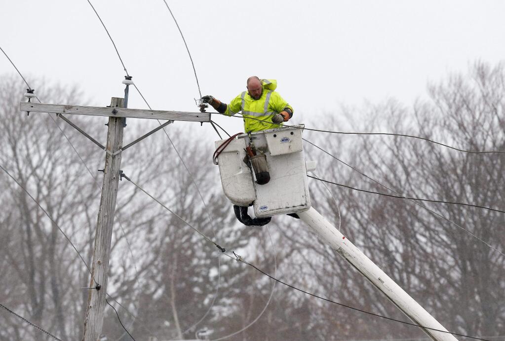 A utility worker repairs power lines in strong wind in Scituate, Mass., Tuesday, Jan. 27, 2015. Massachusetts was pounded by snow and lashed by strong winds early Tuesday as bands of heavy snow left some towns including Sandwich on Cape Cod and Oxford in central Massachusetts reporting more than 18 inches of snow. (AP Photo/Michael Dwyer)