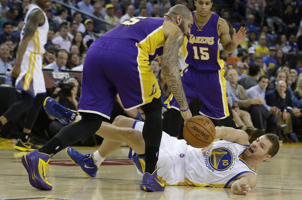 Golden State Warriors forward David Lee, bottom, reaches for the ball under Los Angeles Lakers forward Carlos Boozer during the first half of an NBA basketball game in Oakland, Calif., Monday, March 16, 2015. (AP Photo/Jeff Chiu)