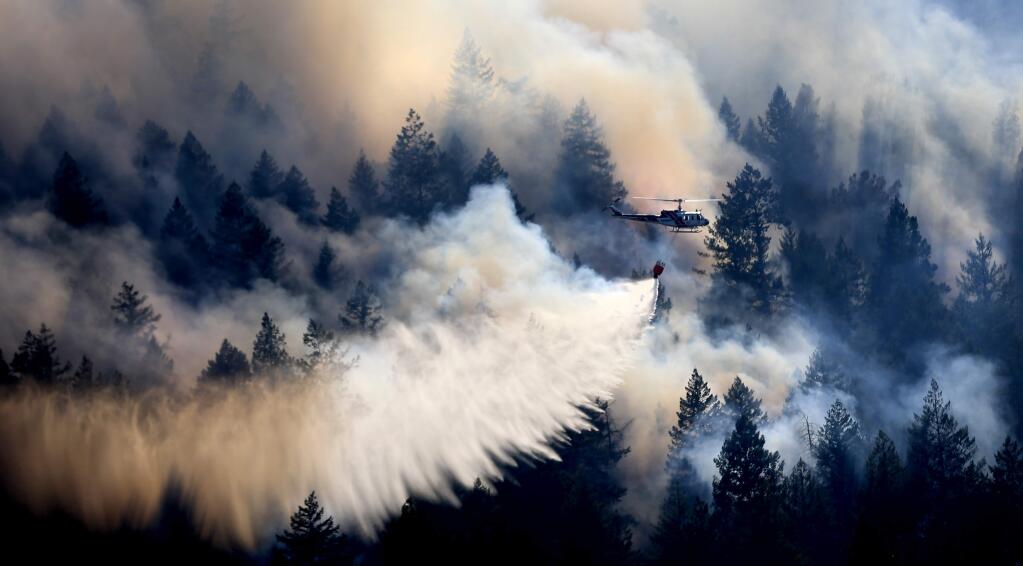 A Cal Fire helicopter makes a drop on the Golf fire at the foot Clear Lake's Mount Konocti on the Buckingham Peninsula on Thursday, Aug 8, 2019. (KENT PORTER/ PD)