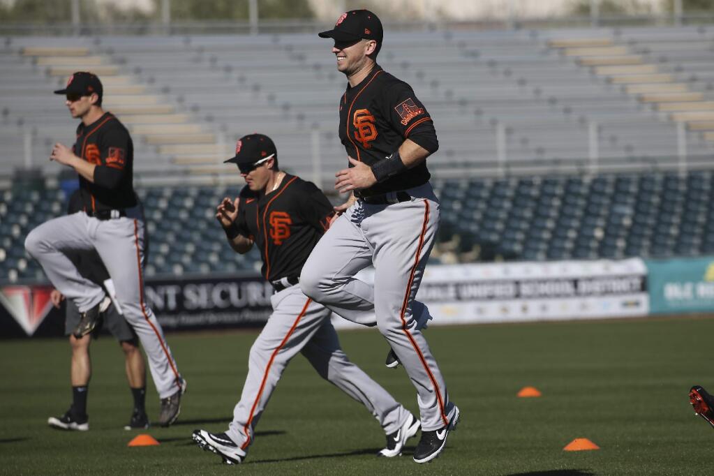 San Francisco Giants catcher Buster Posey, right, jumps in the air as he warms up with teammates during spring training workouts for pitchers and catchers Wednesday, Feb. 12, 2020, in Scottsdale, Ariz. (AP Photo/Ross D. Franklin)