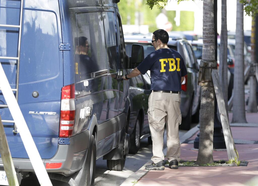 An FBI agent retrieves equipment from a van as he prepares to re-enter the offices of the Confederation of North, Central America and Caribbean Association Football (CONCACAF) Wednesday, May 27, 2015, in Miami Beach, Fla. Swiss prosecutors opened criminal proceedings into FIFA's awarding of the 2018 and 2022 World Cups, only hours after seven soccer officials were arrested Wednesday pending extradition to the U.S. in a separate probe of 'rampant, systemic, and deep-rooted' corruption. (AP Photo/Wilfredo Lee)