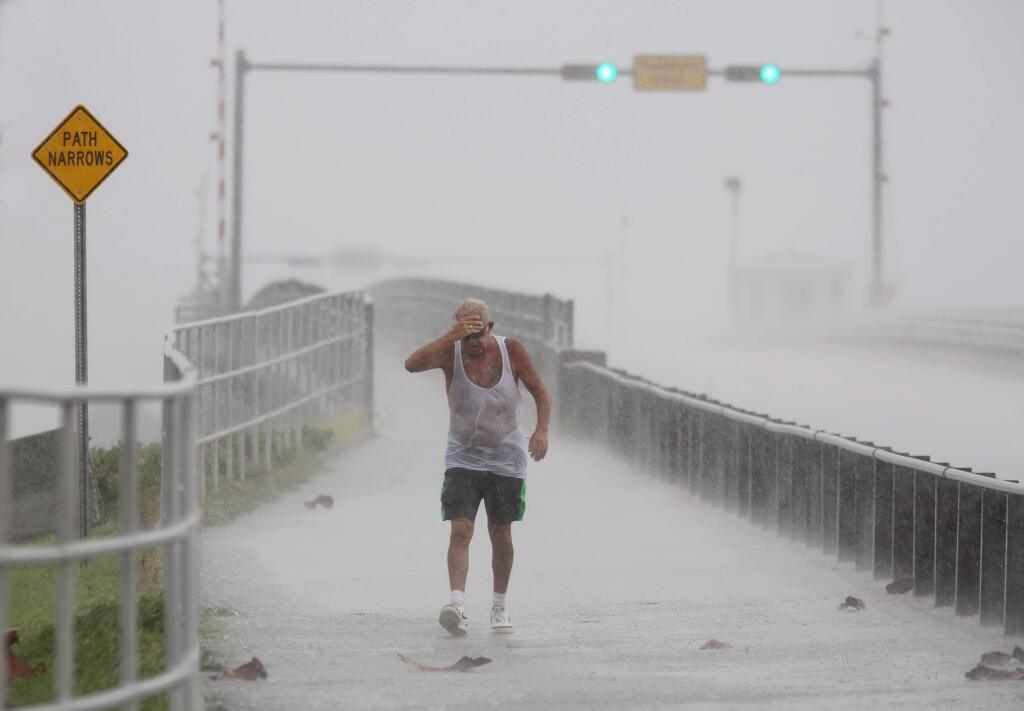 Steve Pearson, of Clearwater, is pummeled by a squall of rain during a walk on the Dunedin Causeway as thunderstorms moved through Pinellas County bringing wind and heavy rain, Monday, Aug. 29, 2016, in Dunedin, Fla. Authorities at some locations in the Tampa-St. Petersburg area of Florida are hauling out sandbags to offer residents amid predictions of heavy rains from a storm system heading to the southeast Gulf of Mexico. (Douglas R. Clifford/Tampa Bay Times via AP)