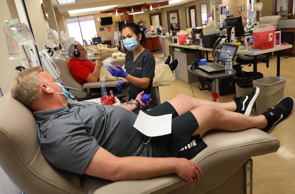 Phlebotomist Mel Estella, right, talks to blood donor Roy Salmon, while filling vials of his blood to be tested for the presence of coronavirus antibodies, at the Vitalant blood donation center in Santa Rosa on Tuesday, June 9, 2020. (Christopher Chung/ The Press Democrat)
