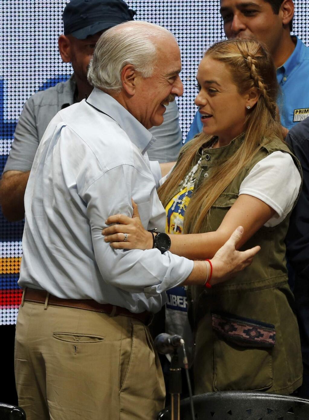 Colombia's former President Andres Pastrana, left, embraces Lilian Tintori, left after a news conference of international observers of a symbolic referendum in Caracas, Venezuela, Sunday, July 16, 2017. Hundreds of thousands of Venezuelans lined up across the country and in expatriate communities around the world Sunday to vote in a symbolic rejection of President Nicolas Maduro's plan to rewrite the constitution, a proposal that's raising tensions in a nation battered by shortages and anti-government protests. (AP Photo/Ariana Cubillos)