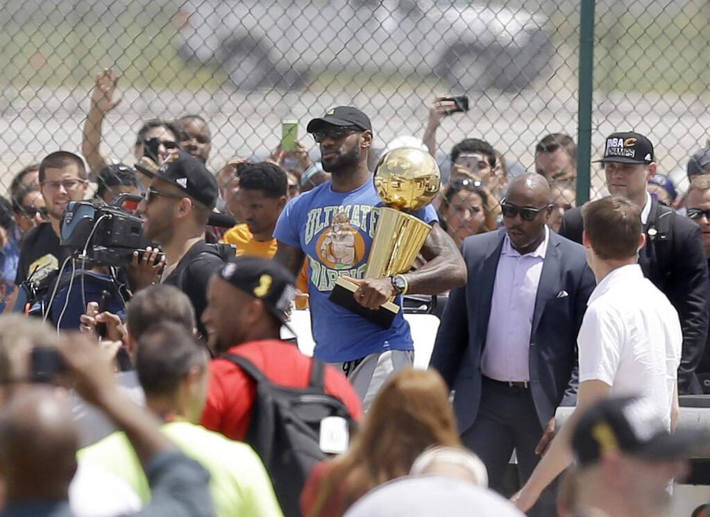 Cleveland Cavaliers' LeBron James carries the NBA Championship trophy after arriving in Cleveland, Monday, June 20, 2016. (AP Photo/Tony Dejak)