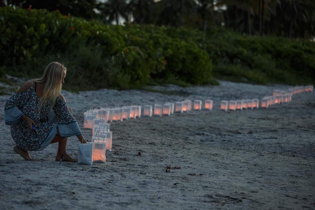 Lilly Folds lights paper lanterns during a candlelight vigil and paper balloon release at Jupiter Inlet Park, Monday, July 27, 2015, for teenagers Austin Stephanos and Perry Cohen in Jupiter, Fla. The teens were last seen Friday afternoon buying fuel near Jupiter and were believed to have been heading toward the Bahamas. (Thomas Cordy/The Palm Beach Post via AP)