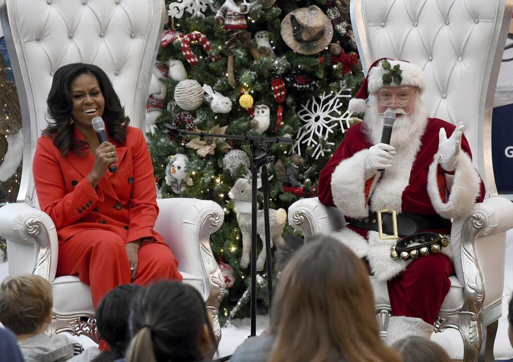 Santa Claus and former first lady Michelle Obama answer questions after Obama read 'The Night Before Christmas' to a group of patients at Children's Hospital Colorado in Aurora, Colo., on Thursday, Dec. 13, 2018. (AP Photo/Thomas Peipert)