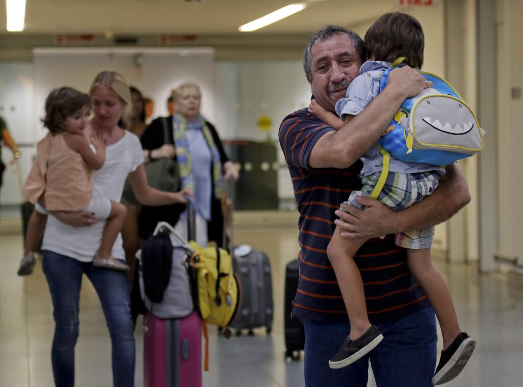 Juan Rojas, right, of Queens, hugs his 4-year-old grandson Elias Rojas, as his daughter-in-law Cori Rojas, left, carries her daughter Lilly, 3, through the terminal at JFK airport after Cori arrived on a flight from San Juan, Puerto Rico, Tuesday, Sept. 26, 2017, in New York. Cori Rojas, who is a school teacher in Puerto Rico, fled Puerto Rico with her children after Hurricane Maria left the island devastated and will stay with her in-laws in Queens while her husband, who works for a global insurance firm chose to stay behind. (AP Photo/Julie Jacobson)