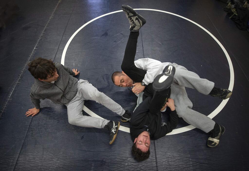 Elsie Allen assistant wrestling coach Alex Duerr demonstrates a move on Edgar Reyes while Kevin Escobar watches during practice on Thursday. The team shared the NBL Redwood title, only the sixth pennant in school history. (John Burgess / The Press Democrat)
