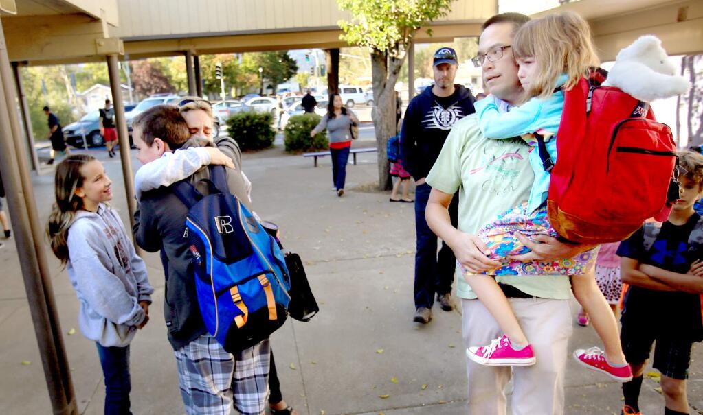 Cobb Elementary School was spared from the Valley fire (it sustained heat and smoke damage) still students are being re-routed to Middletown High and middle school to attend their classes. Cobb Elementary teacher Marc Morita and daughter Lily Monday were accompanied to class by Heidi Hennek, and her daughter Gracelynn, embracing her nephew Beau Davis who lost his home to the blaze, Sept. 28, 2015. (Kent Porter / Press Democrat) 2015