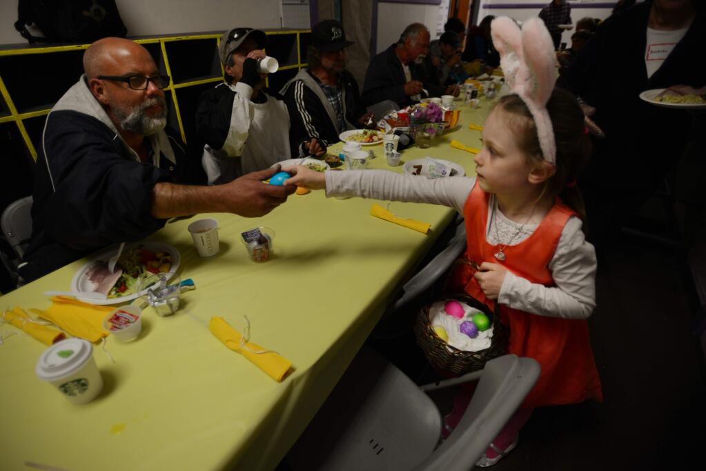 Alegria Prosser, 5, right, hands out a colored Easter egg to Ed Ballard, left, who has been homeless for eight years, during the 10th Annual Easter Brunch for the Homeless held Sunday at the SOMA Church Community in Santa Rosa. April 16, 2017.(Photo: Erik Castro/for The Press Democrat)