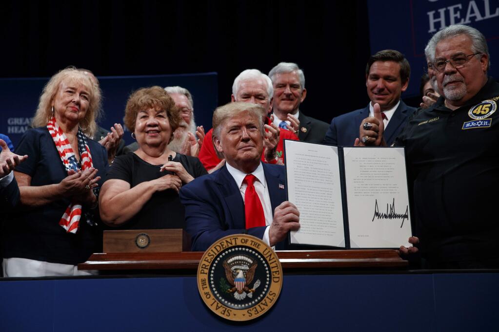 President Donald Trump shows an executive order about Medicare at the Sharon L. Morse Performing Arts Center, Thursday, Oct. 3, 2019, in The Villages, Fla. (AP Photo/Evan Vucci)