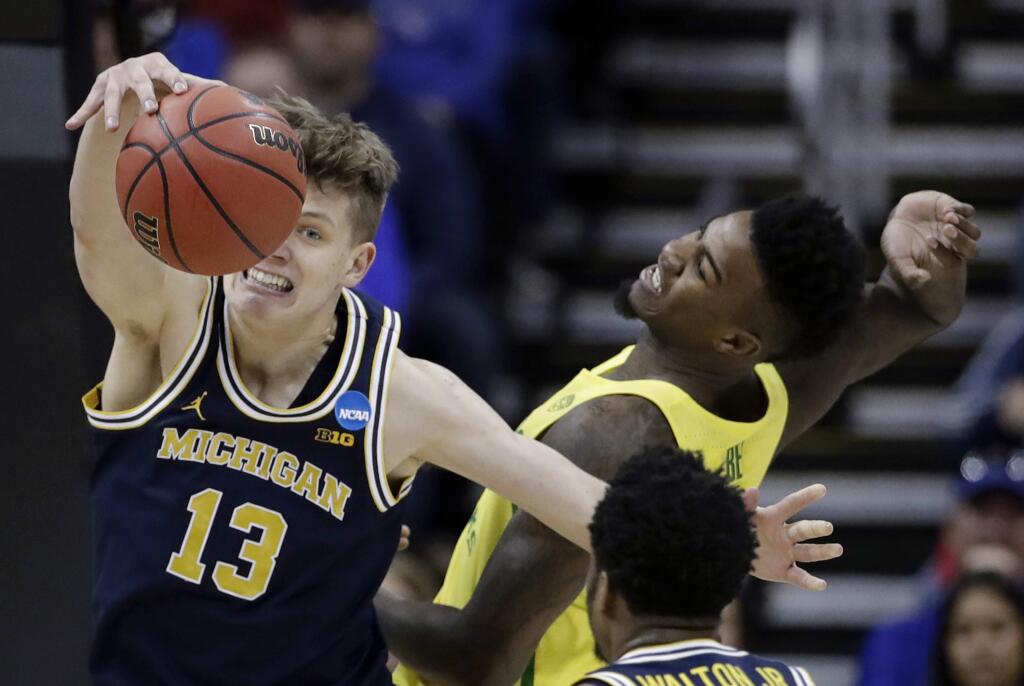 Michigan forward Moritz Wagner (13) fights for a rebound with Oregon forward Jordan Bell during the first half of a regional semifinal of the NCAA men's college basketball tournament, Thursday, March 23, 2017, in Kansas City, Mo. (AP Photo/Charlie Riedel)